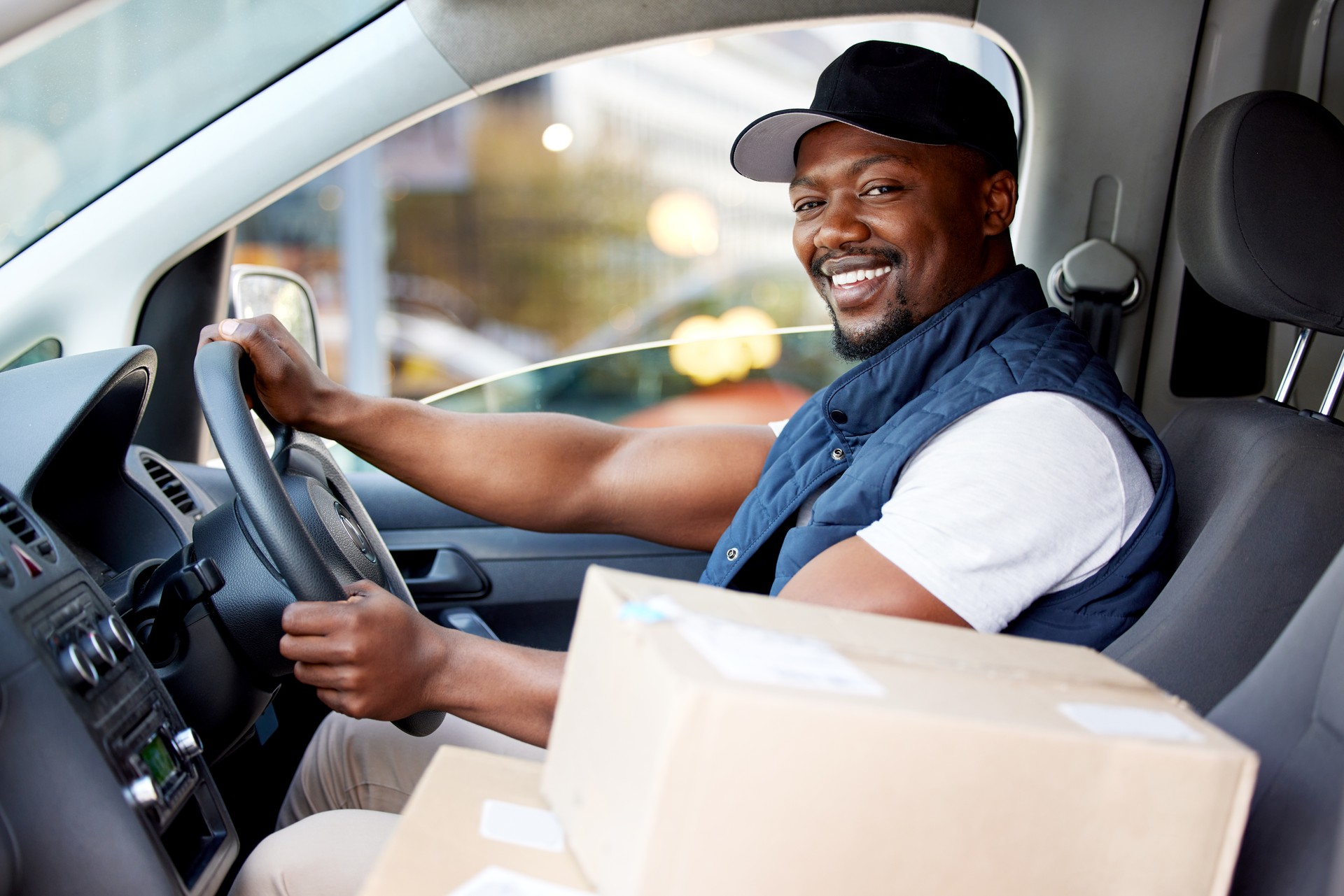 Shot of young man delivering a package while sitting in a vehicle